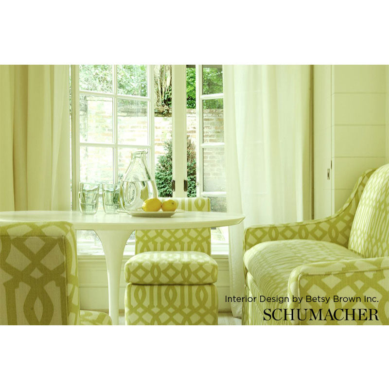 Sunlit breakfast nook with pale yellow geometric upholstery, round white table, and glass pitcher with lemons.