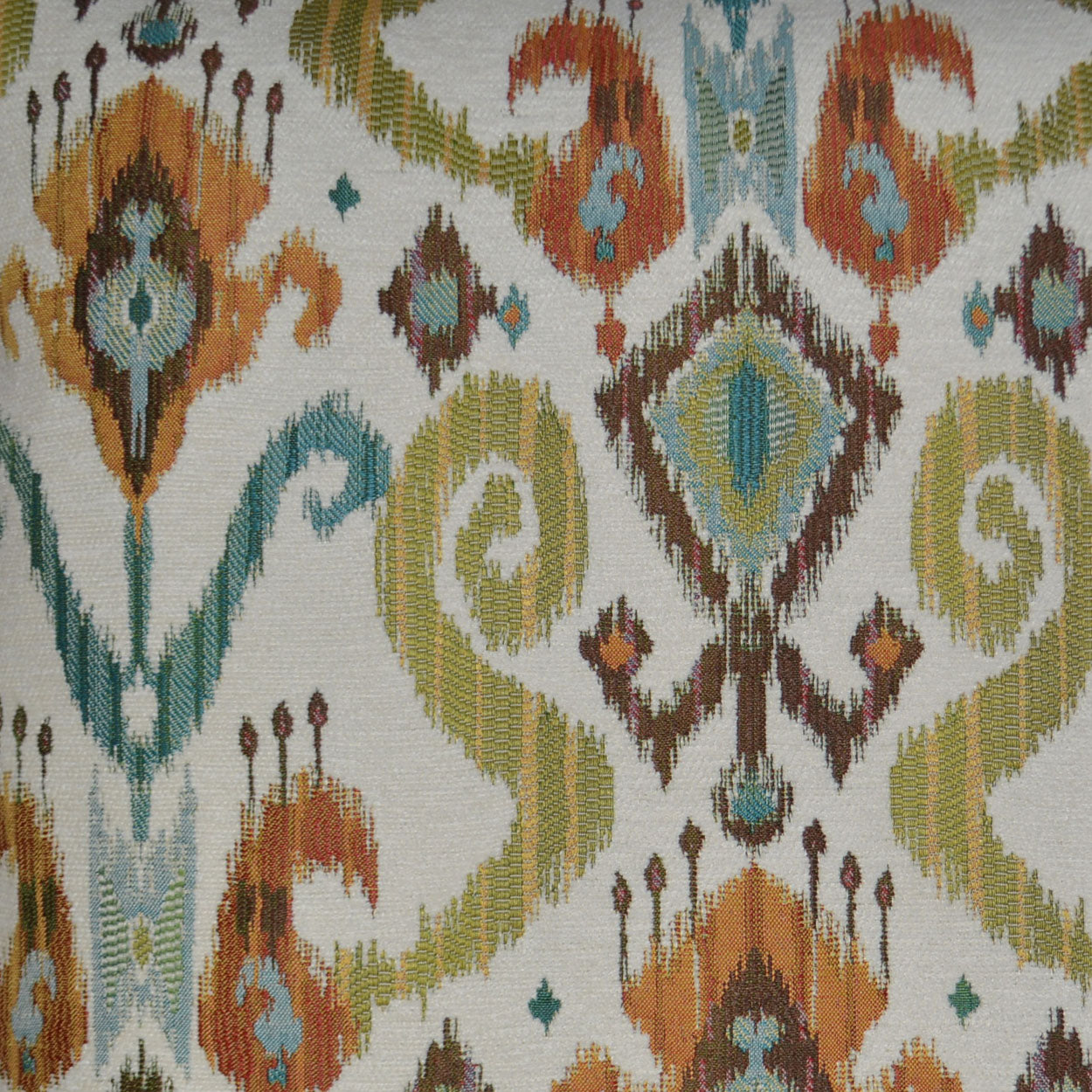 24" x 24" decorative Ikat pillow with teal, orange, olive, and brown motifs on a cream background.