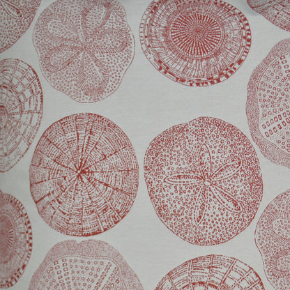 Red 24" x 24" sand dollar pillow with circular sea urchin/sand dollar motifs on light fabric.