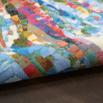 Close-up of a colorful patchwork woven rug with blue, red, yellow blocks on dark wood floor.