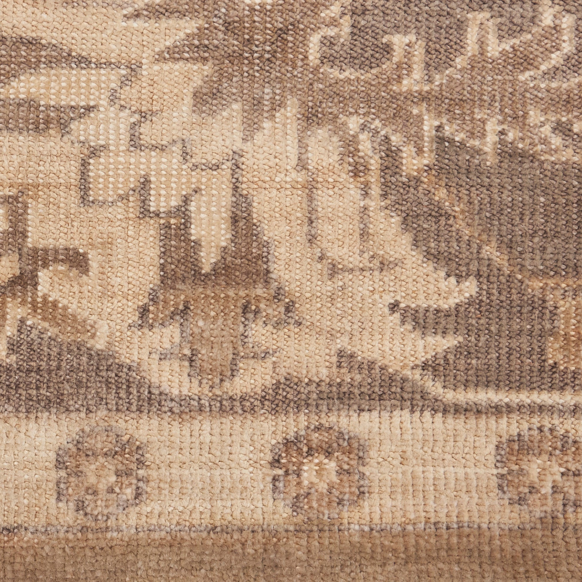 Beige and brown woven rug with abstract tribal motifs, branch-like shapes, and small circular medallions.