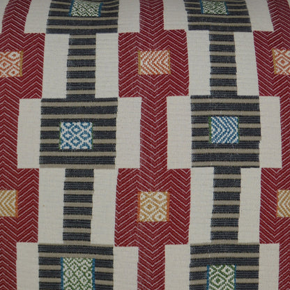 Pillow featuring a geometric pattern with red blocks, navy striped panels, cream gaps, and small blue and orange accents.