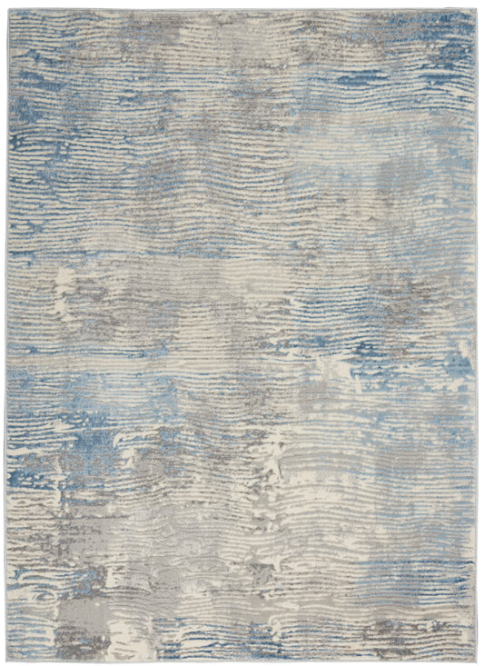 Rectangular abstract rug in blue, gray and beige tones with a distressed, wavy pattern and soft textured pile.