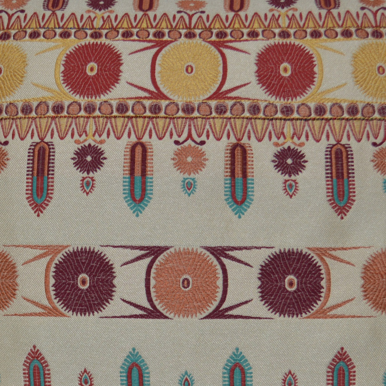 Vibrant woven pillow with sunburst circle motifs and teardrop borders in red, yellow, orange, teal on beige.