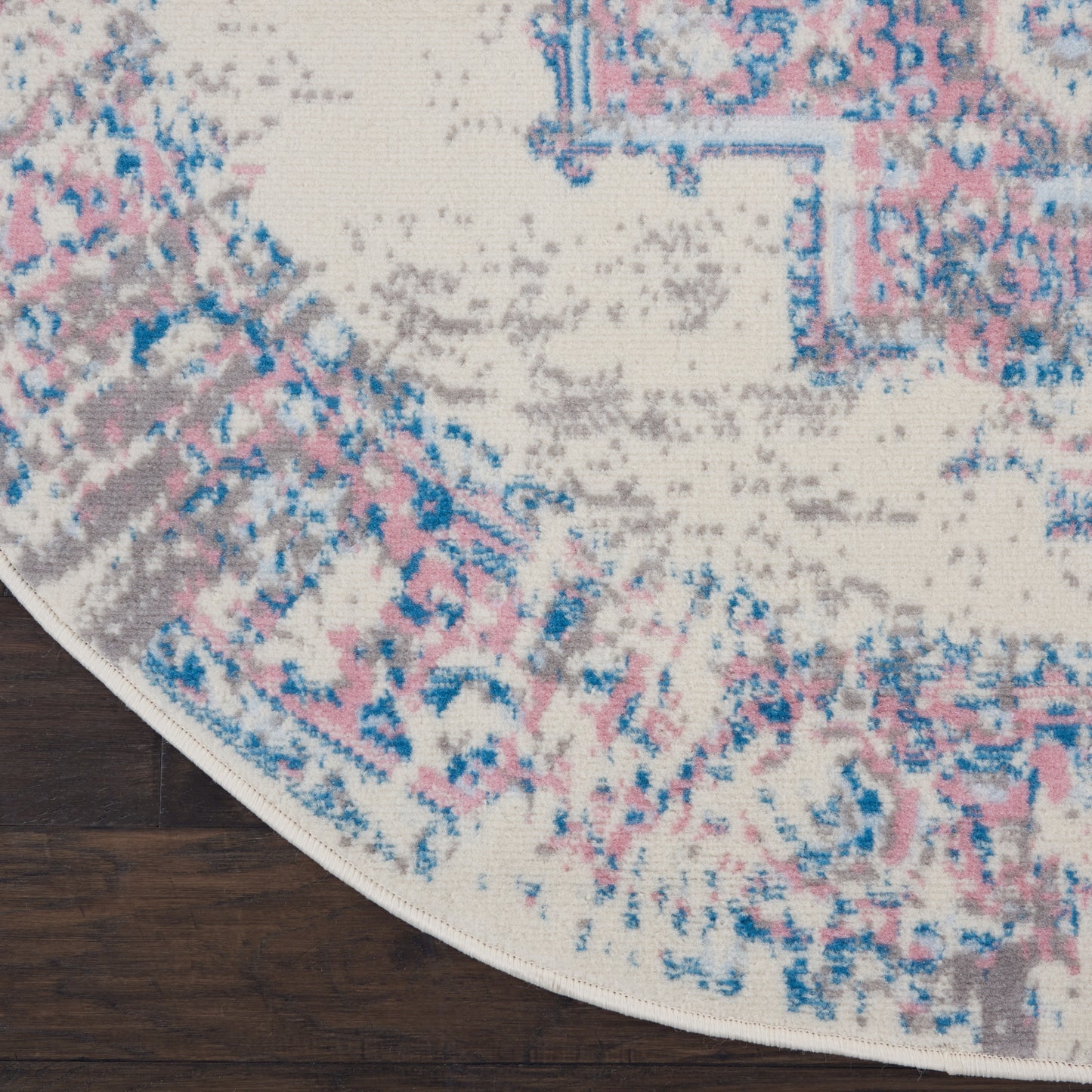 Round cream area rug with pink, blue, and gray distressed pattern; plush textured pile for modern vintage living spaces.