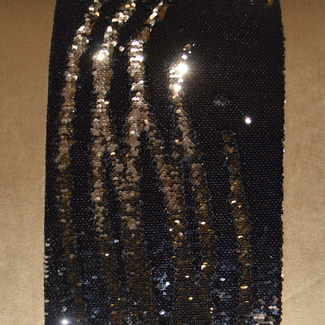 Black fabric with vertical gold sequin stripes, shimmering, suitable for evening dress or accessories.