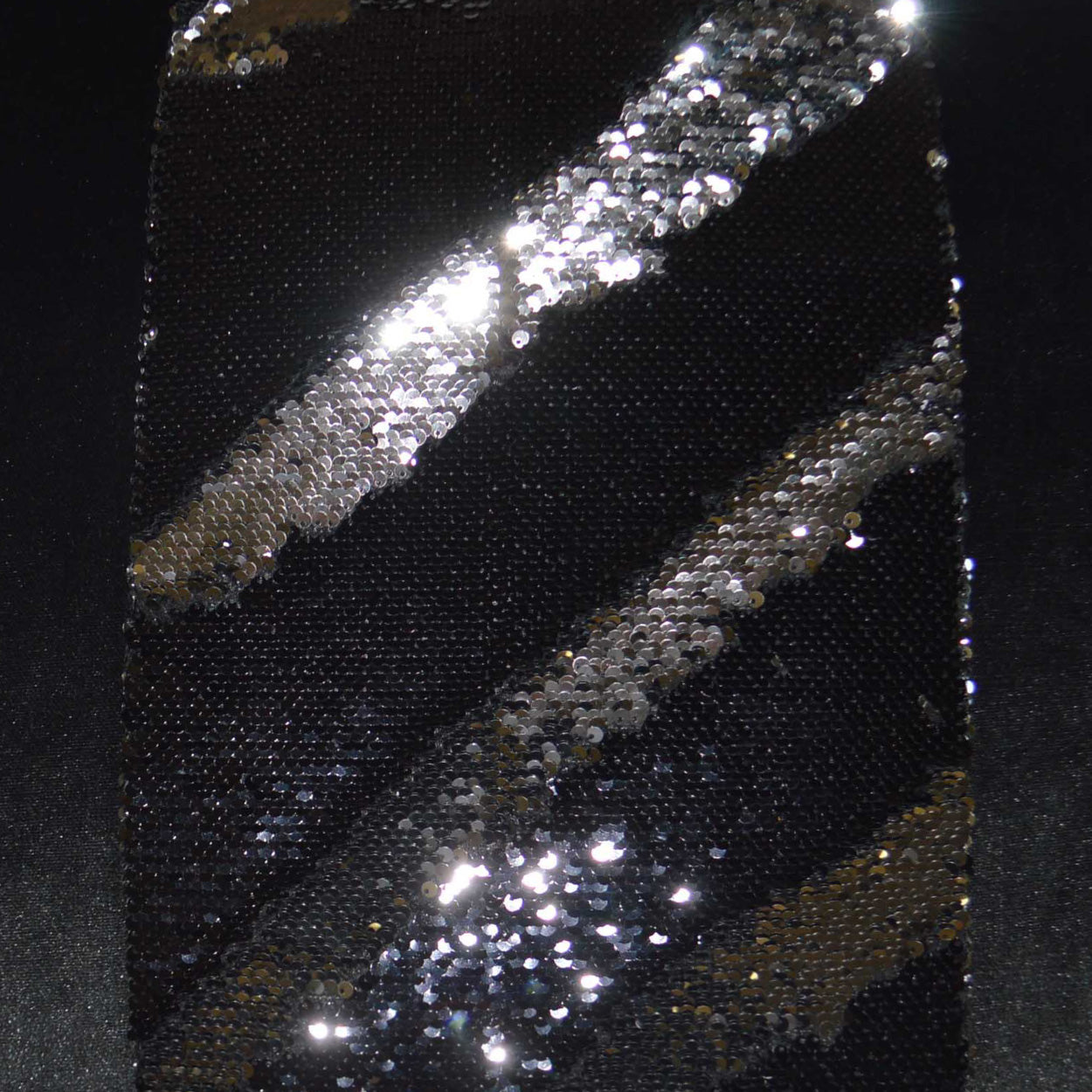 Black fabric with diagonal silver sequin stripes, creating a sparkling metallic pattern.