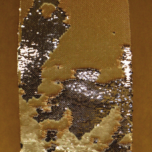 Gold sequin fabric strip with silver-black reflective sequins on bronze backing; glamorous, sparkly garment material.