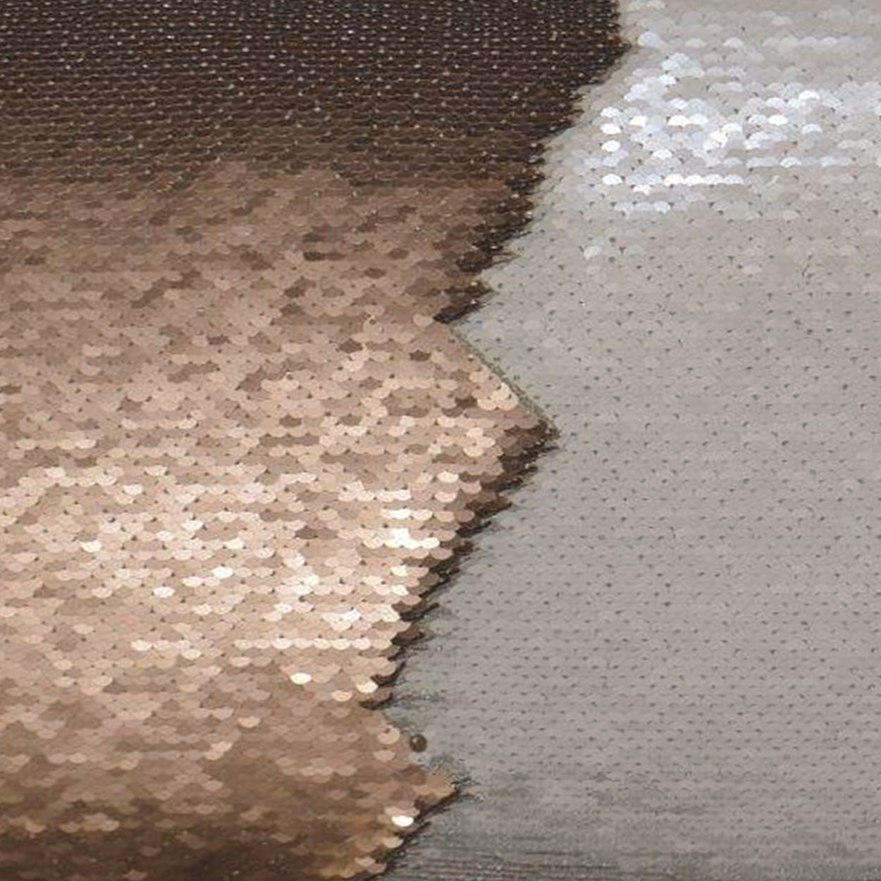 Two-tone sequin fabric: copper/gold left fading to silver right, shimmering for dresses or decor.