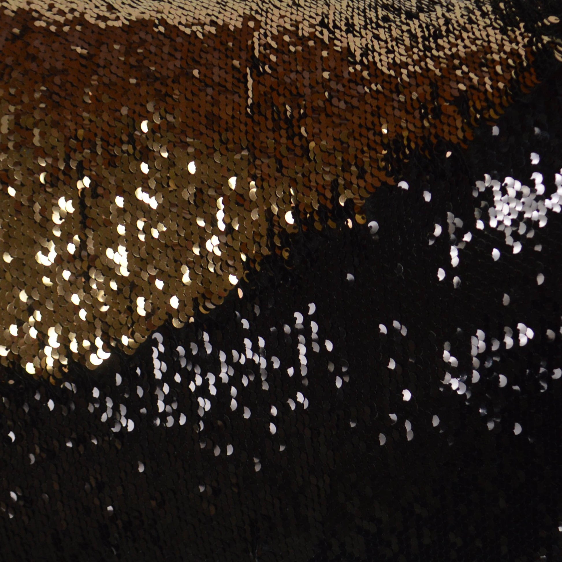 Gold and black sequin fabric with a diagonal color split and shimmering metallic texture for evening wear.