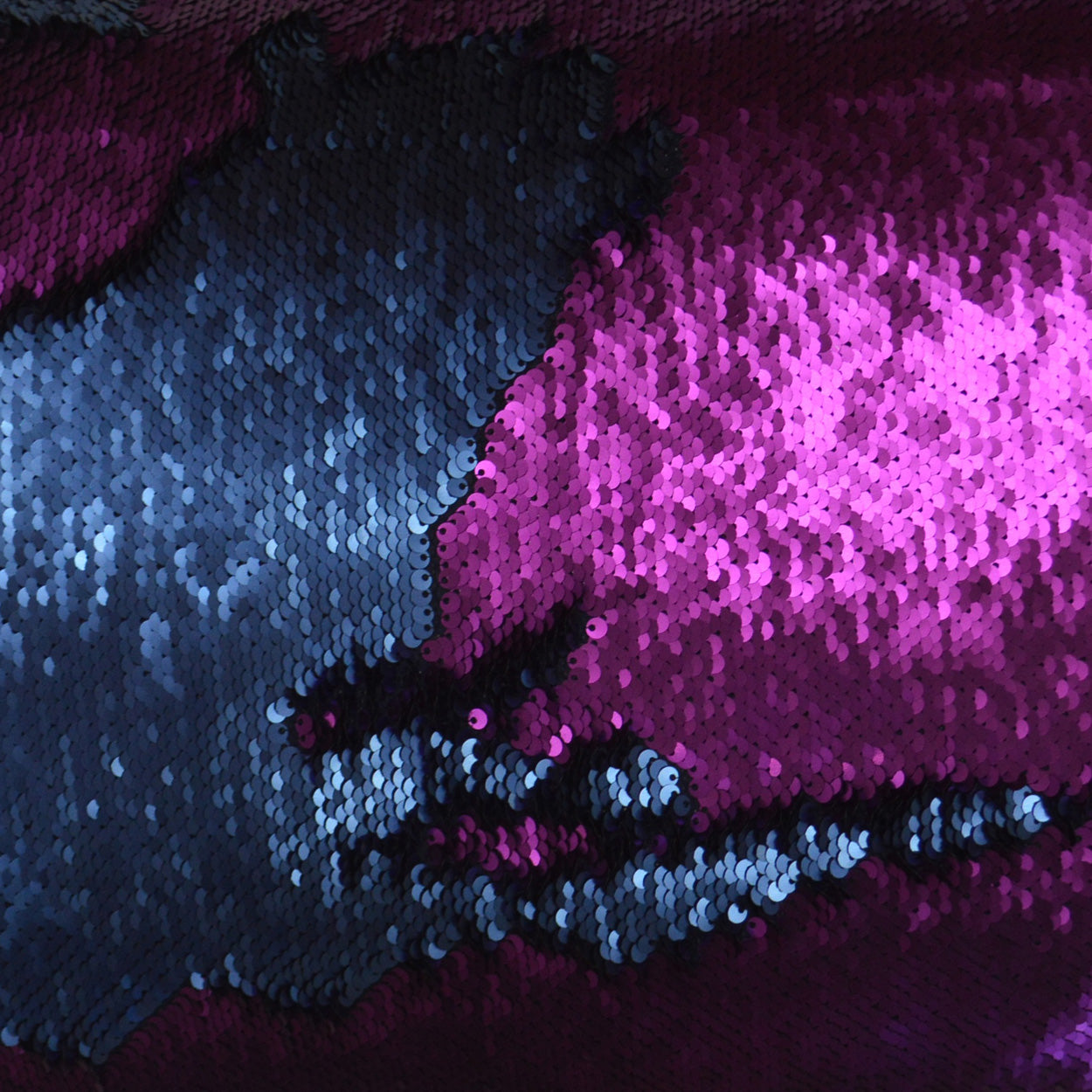 Close-up of blue and pink sequin fabric with a shimmering, iridescent surface for evening wear.