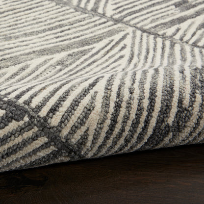 Close-up of a gray and off-white striped area rug with a textured loop-pile on a dark wood floor.