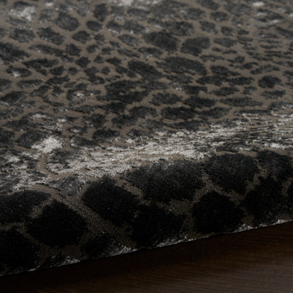 Close-up of a charcoal leopard-print plush rug with a thick pile on a dark wooden floor.