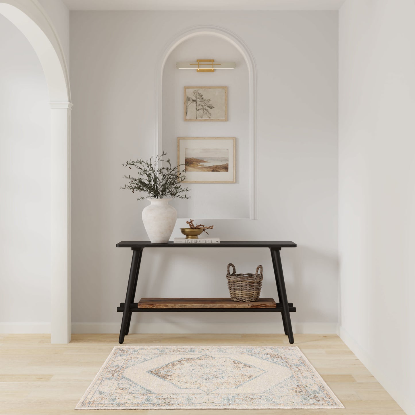 Neutral entryway with dark wood console, vase of greenery, woven basket, arched wall niche with framed art, and a light rug.