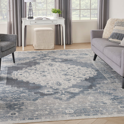 Blue-gray distressed oriental rug anchors a bright living room & gray sofa, white console & beige ottoman.