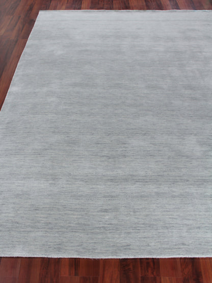Light gray rectangular area rug with subtle texture on dark hardwood floor.