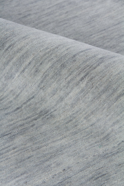 Close-up of light grey-blue marl rug with a soft diagonal weave; indoor hand-loomed texture.