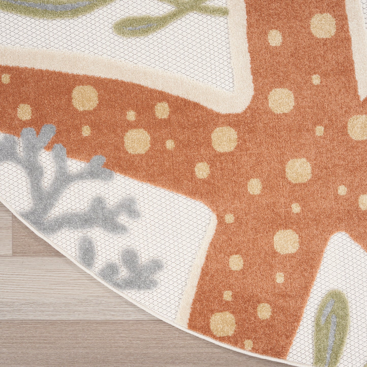 Orange rug with cream polka dots and pale blue botanical accents along a light border on a wooden floor