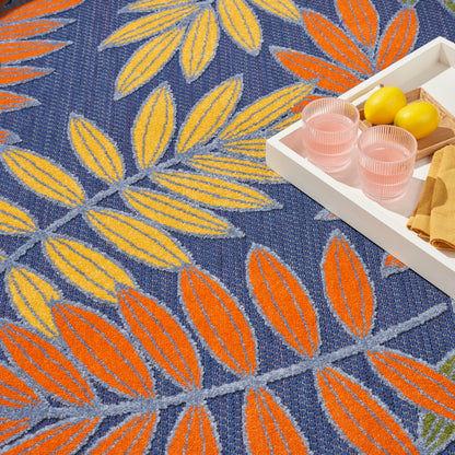 Blue rug with yellow and orange leaf pattern; white tray with pink glasses, lemons, and beige napkins.