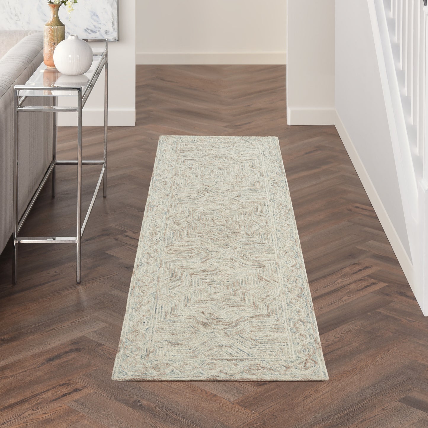 Light beige patterned hallway runner rug on dark wood floor, with a chrome-glass console table to the left.