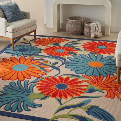 Vibrant floral area rug with large orange and teal petals on beige, blue border; living room with sofa and woven baskets.