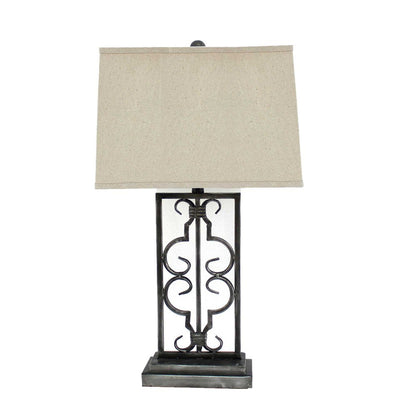 Beige rectangular fabric shade atop a black wrought-iron scrollwork table lamp with a square base.