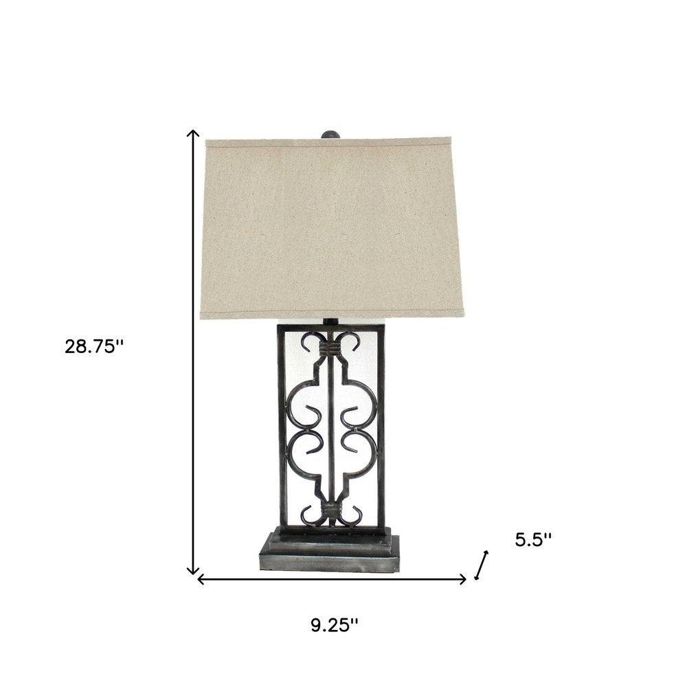 Black wrought-iron table lamp with ornate scrollwork & beige fabric shade; 28.75 in tall, base 9.25 in wide.