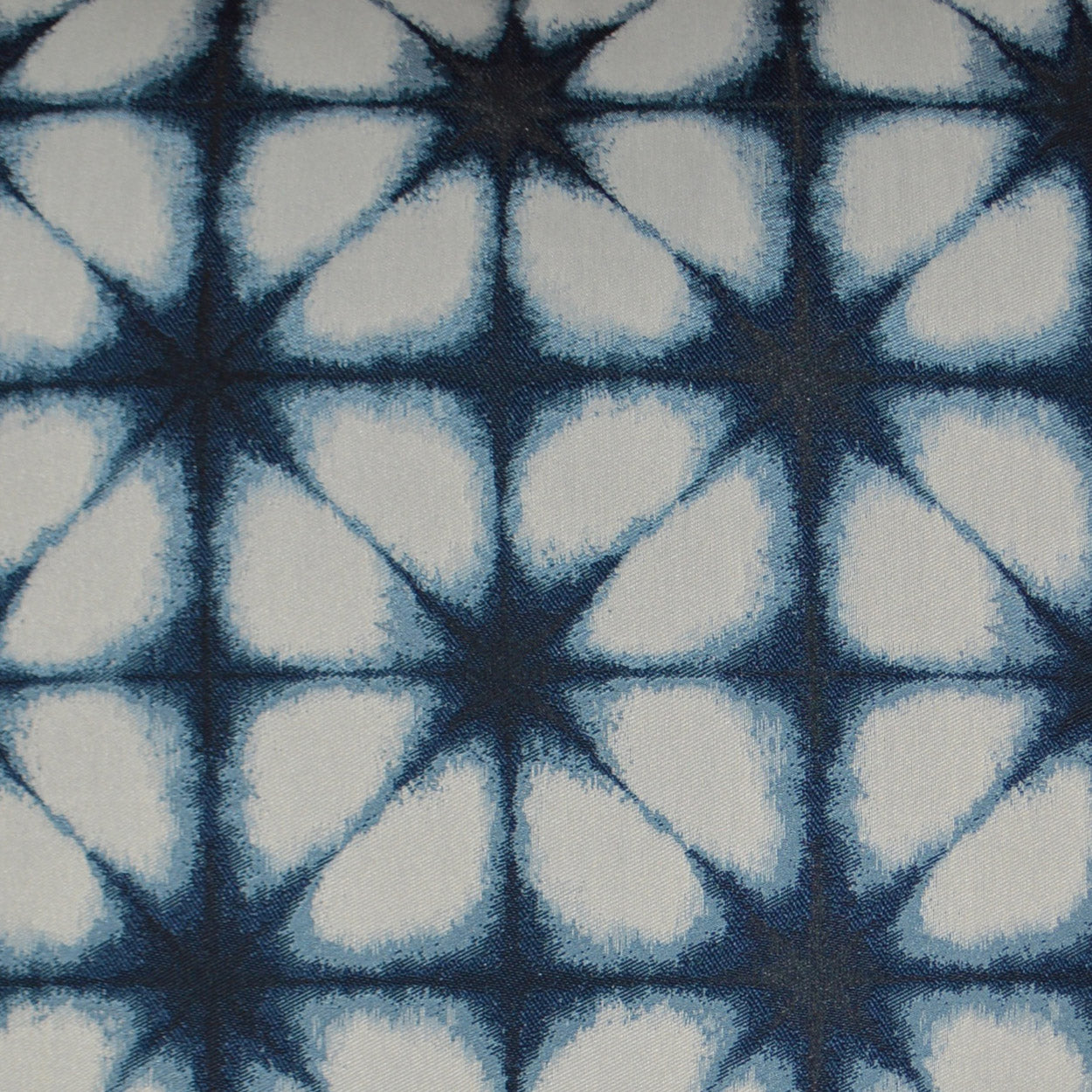 Blue and white fabric with navy starburst motifs in a repeating geometric grid.