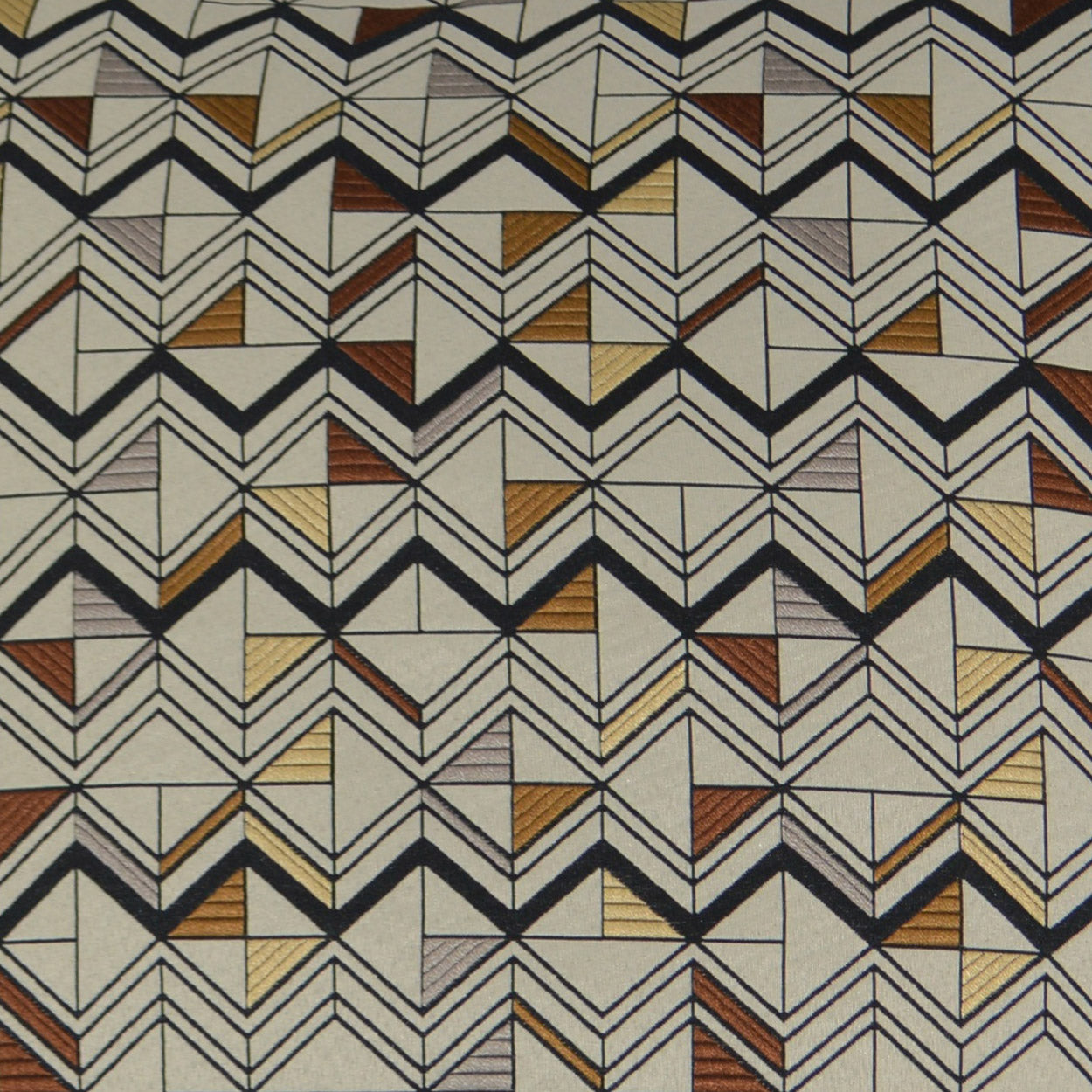 Geometric chevron fabric with black zigzag outlines and small gold, brown, grey blocks on beige background.