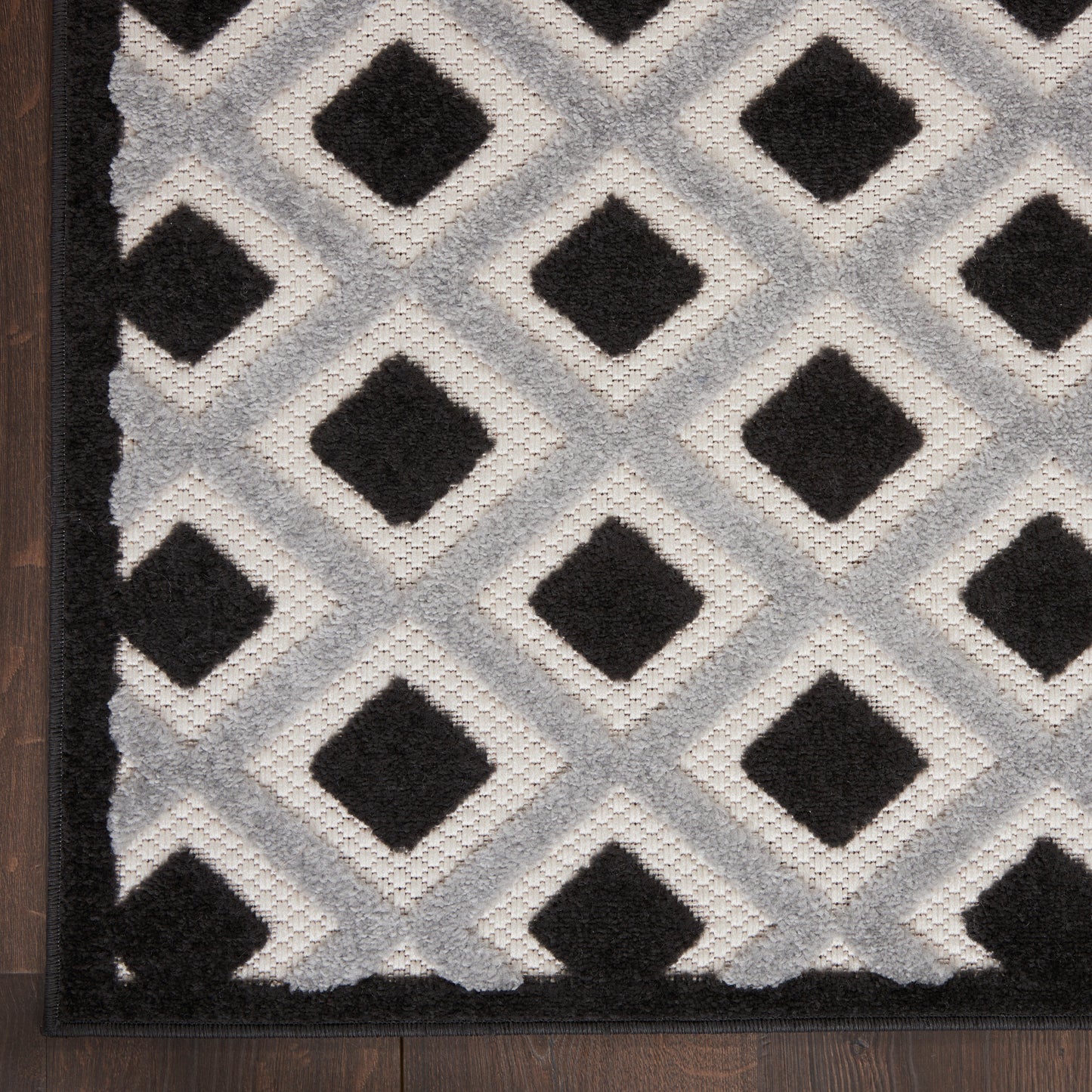 Large neutral gray 9' x 12' rug on wood floor with a dark patterned design; minimalist decor piece.