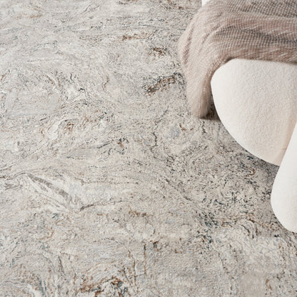 Cream beige textured rug with abstract marbled pattern and a plush beige throw draped over a curved armchair.
