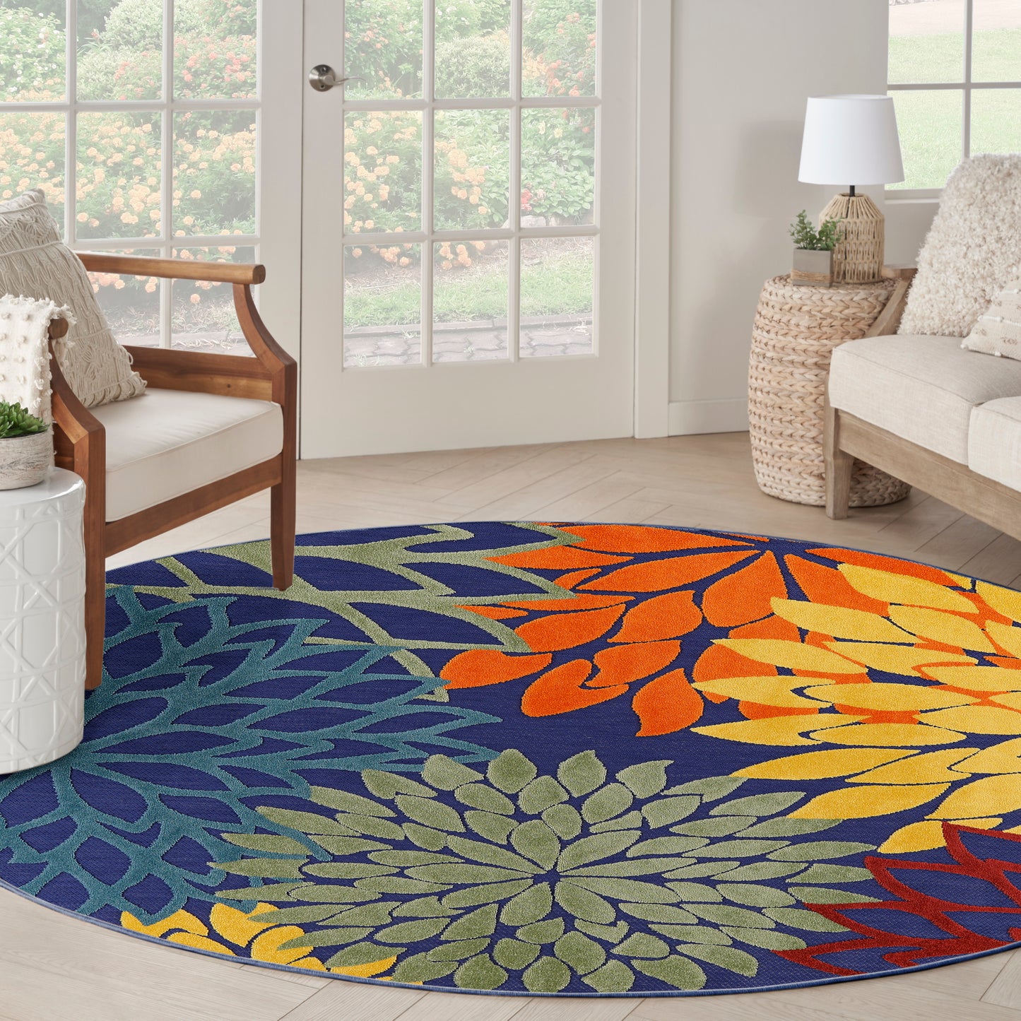 Round rug with bold multicolor floral pattern in blue, green, orange, and yellow in a bright living room.