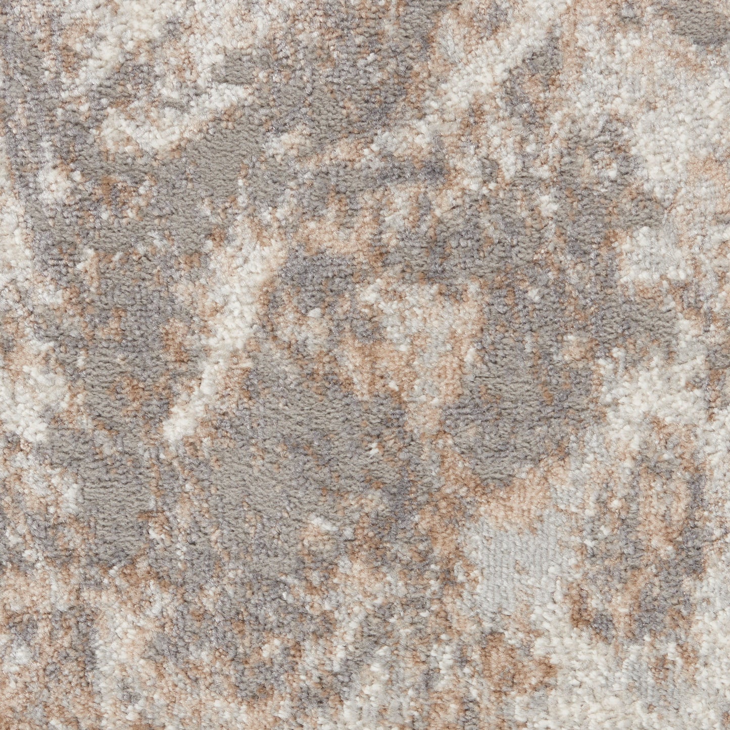 Close-up of a plush area rug with an abstract marbled pattern in beige, taupe and cream.
