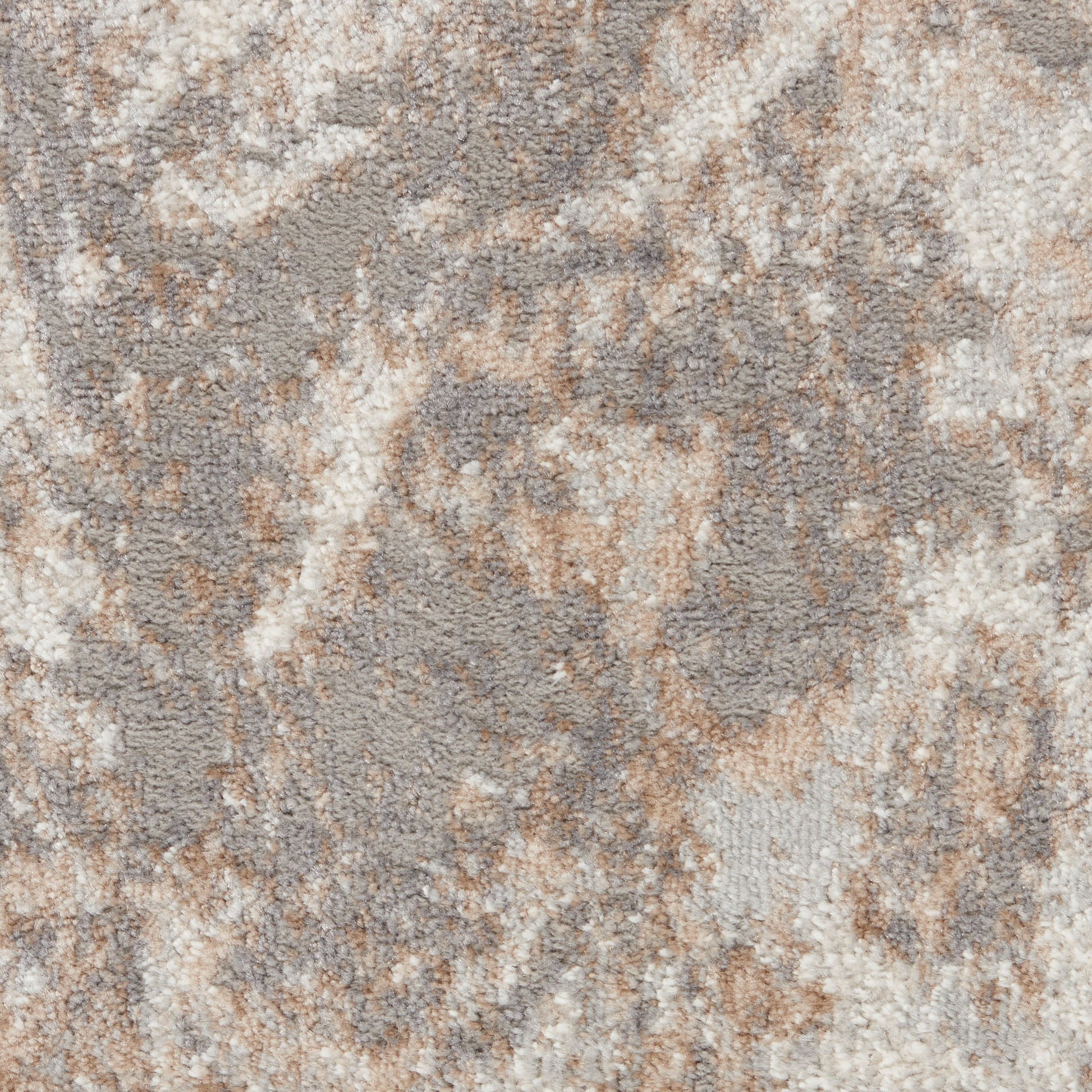 Close-up of a plush area rug with an abstract marbled pattern in beige, taupe and cream.