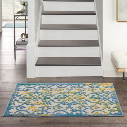 Colorful blue, teal and yellow patterned rug in front of white staircase with dark treads; modern living room.