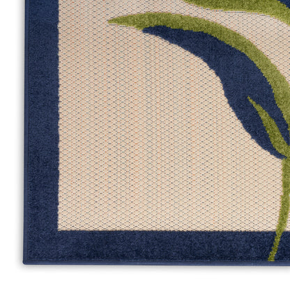 Beige woven rug with deep navy border and abstract green and blue curved arc motif; tufted, modern coastal style.