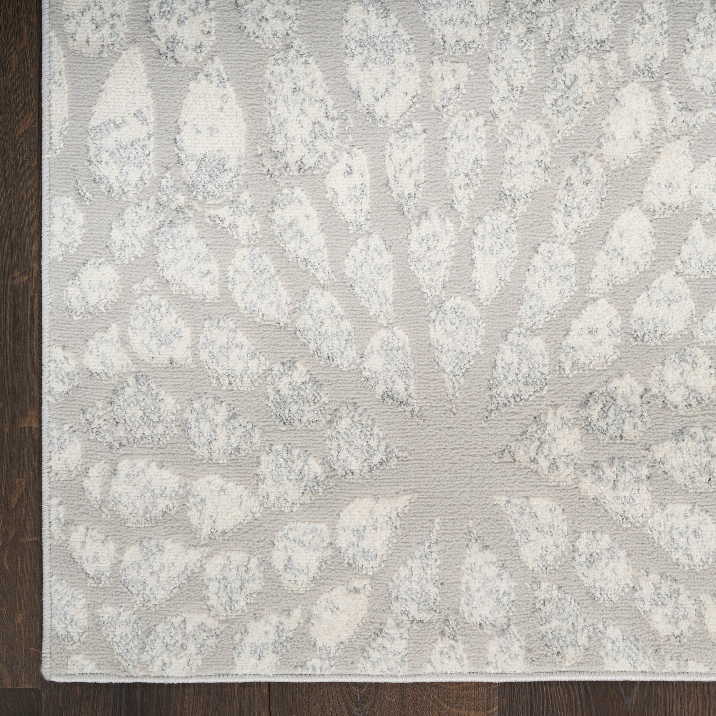 Rectangular pale gray rug with ivory sunburst radiating motif and tufted texture for modern living spaces.