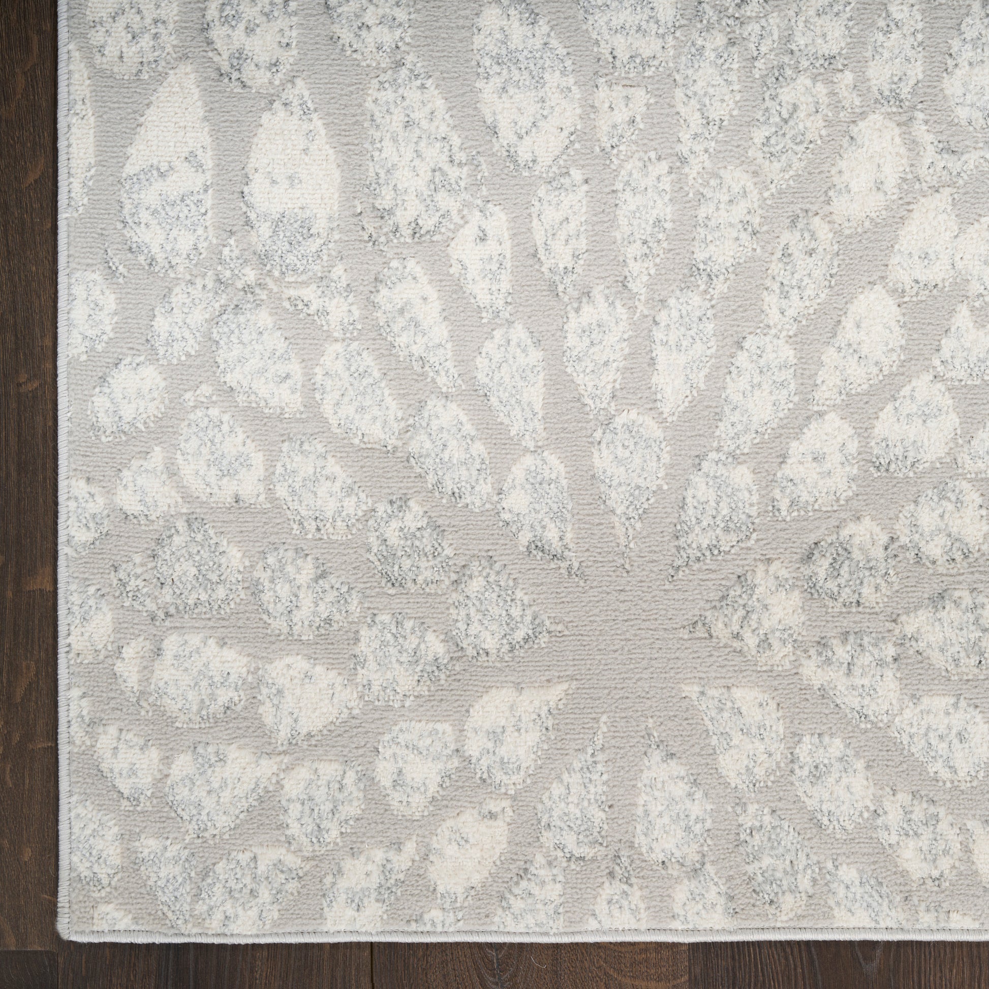 Rectangular pale gray rug with ivory sunburst radiating motif and tufted texture for modern living spaces.