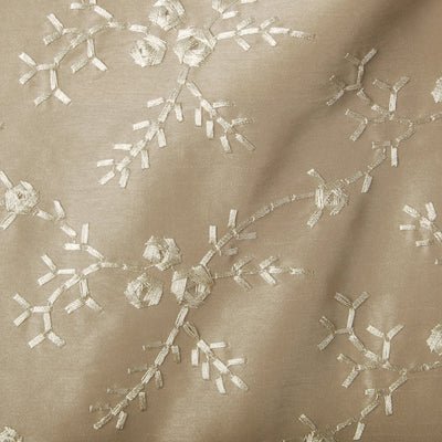 Beige satin upholstery fabric with delicate white snowflake-like embroidery and branch motif; elegant decorative textile.