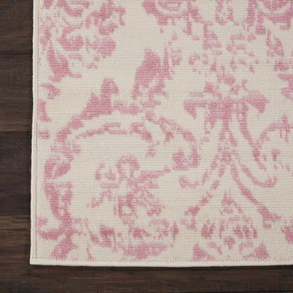 Cream runner rug with pink damask floral pattern and subtle border on dark wood floor.