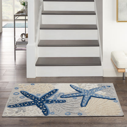 Entryway rug with two blue starfish on beige backdrop, placed on wood floor beside a white staircase with gray treads.