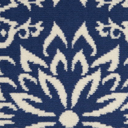 Blue woven rug with bold white floral mandala pattern and geometric petal shapes.