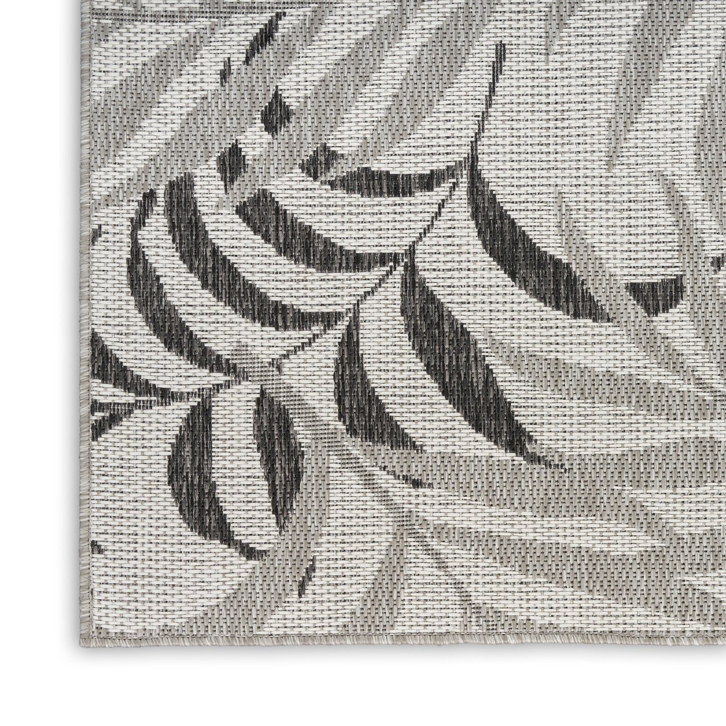 Rectangular gray woven area rug with a tropical leaf pattern and textured jacquard.