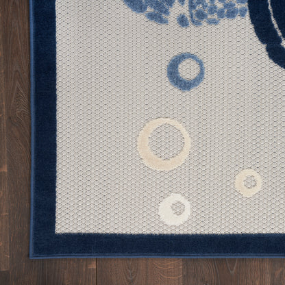 Beige textured area rug with dark navy border and circular blue and ivory motifs on wooden floor.