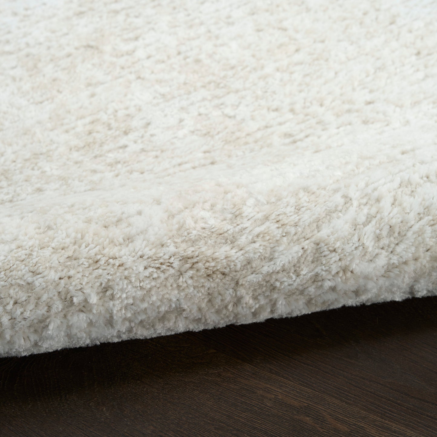 Cream shag area rug with plush high-pile texture on dark wood floor.