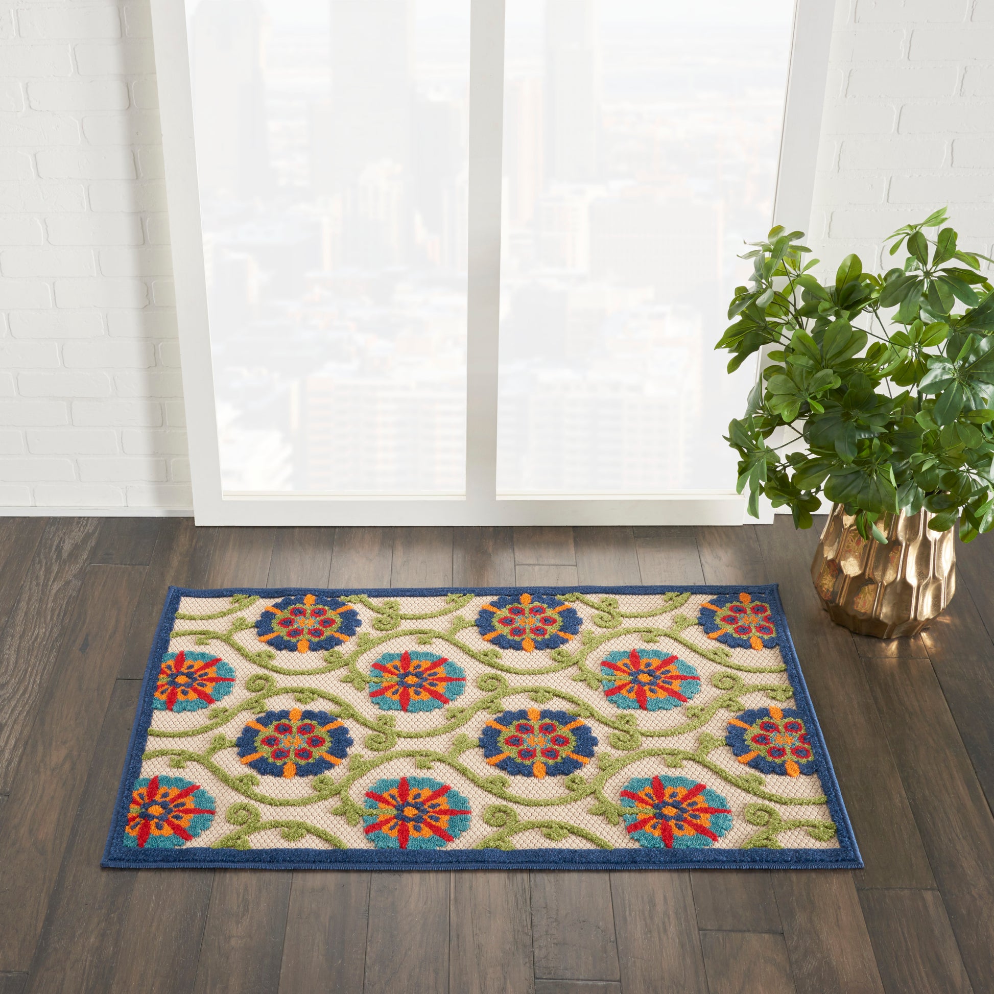 Colorful patterned rug (3' x 4') with blue border and floral medallions on a beige background, placed indoors near a window with a plant.