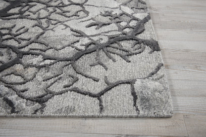 Gray and charcoal patterned area rug with branch-like motif on light wood floor.
