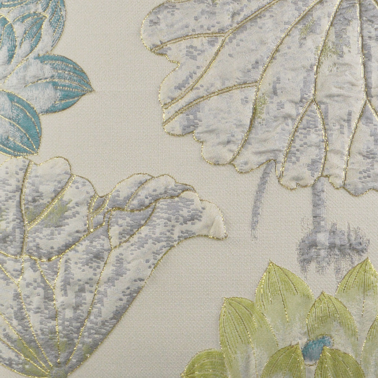 Cream fabric with gold-outlined embroidered leaves in blue, gray, and lime; ornate floral brocade textile.