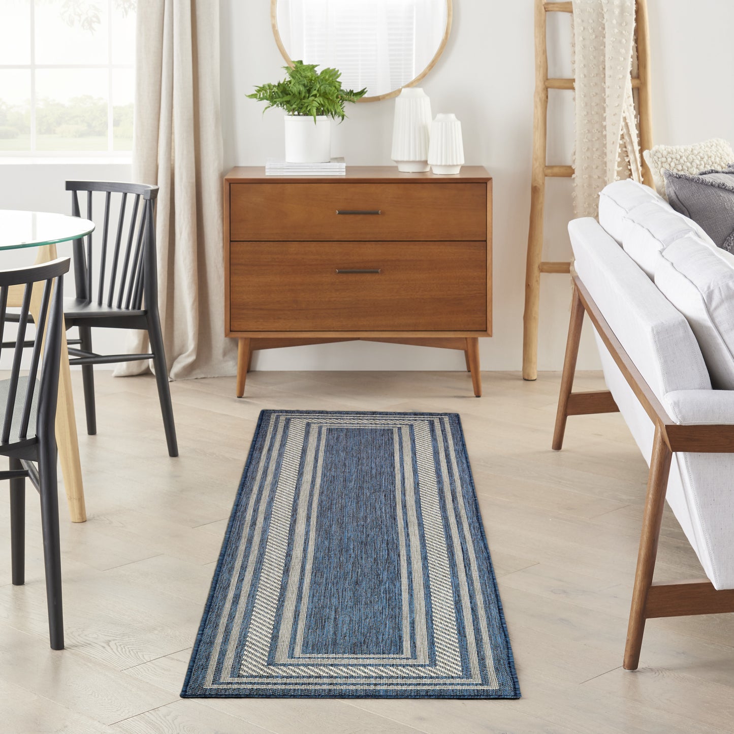 Navy blue striped runner rug with beige borders on a light wood floor in a bright living room.