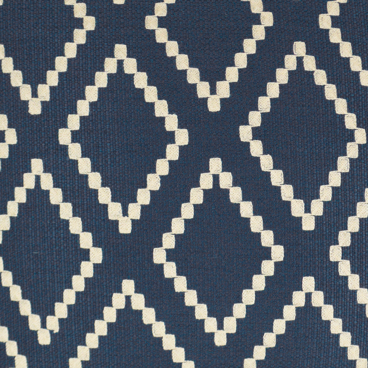 Navy pillow with a white diamond lattice pattern formed by small squares on a geometric woven fabric.